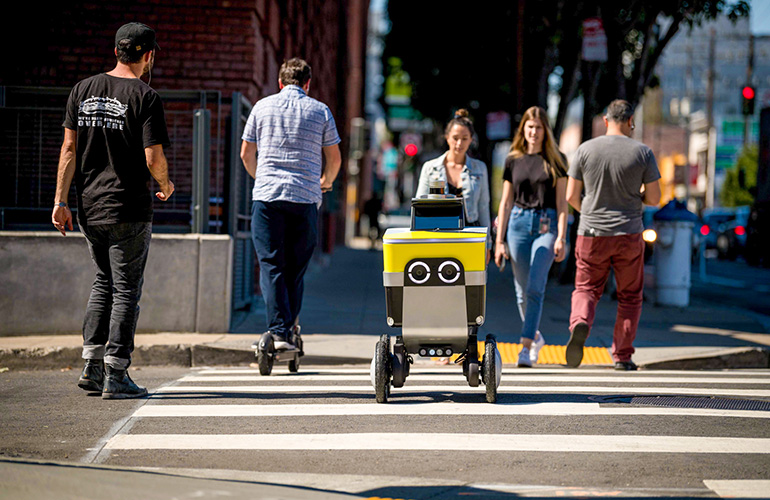 a serve robotics mobile robot crosses the road with pedestrians.