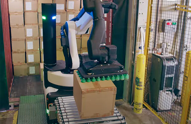 Boston Dynamics' Stretch robot using its suction gripper to drop a package onto a conveyor belt.