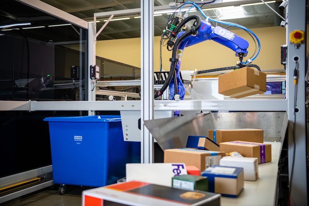 a robotics system placing a variety of packages onto a conveyor belt.