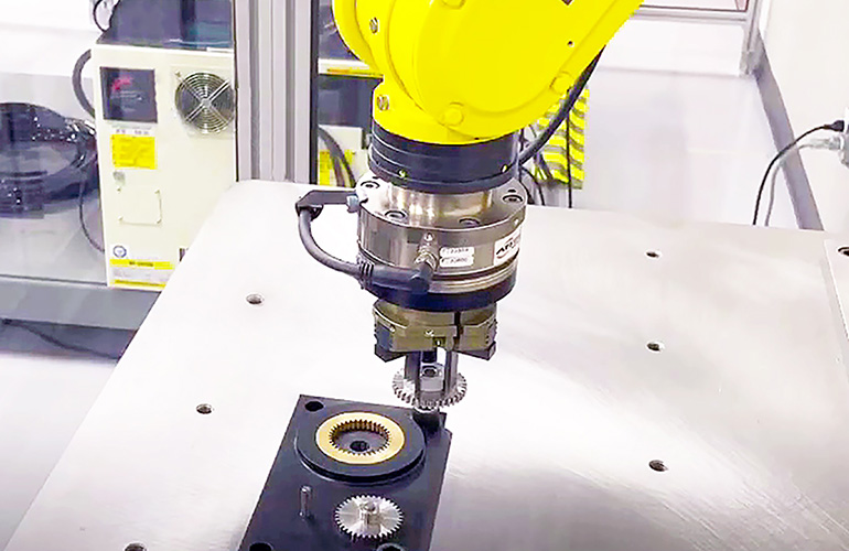 a fanuc robotic meshes gears with a robot gripper.