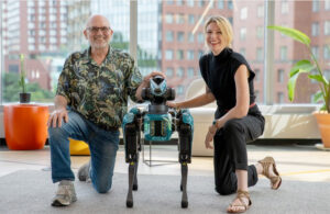 marc raibert and kate darling kneel next to a boston dynamics SPOT robot.