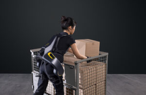 A woman lifting a box while wearing German Bionic's Apogee exoskeleton.