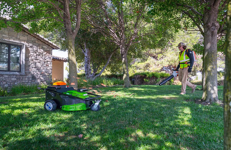 Electric Sheep Robotics' autonomous mower working alongside a landscaper.