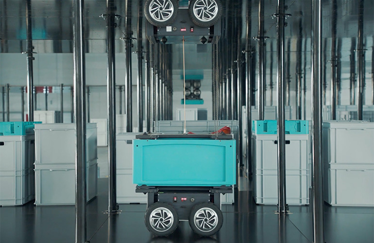 An instock robot transferring a bin to another robot. 