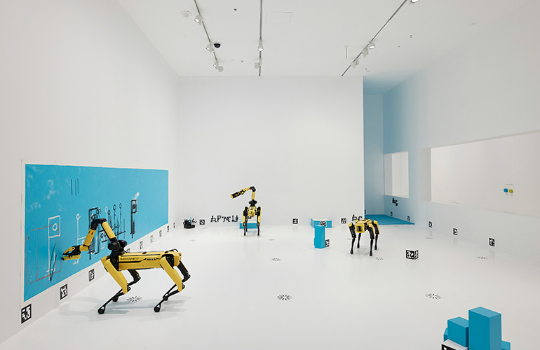 Three robot dogs in an art exhibit each doing their own tasks. 