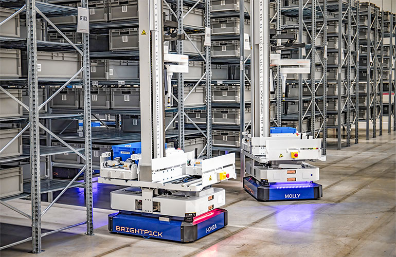 Two Autopicker mobile manipulators in a warehouse aisle.