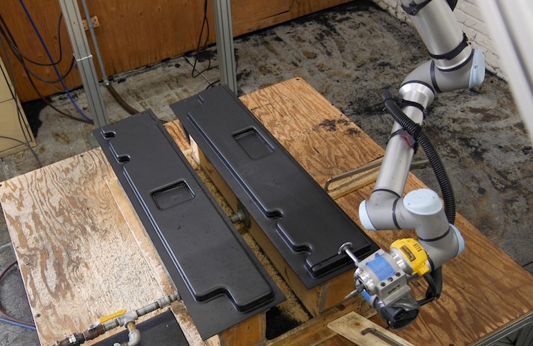 A UR10e cobot arm trimming a thermoformed plastic part.