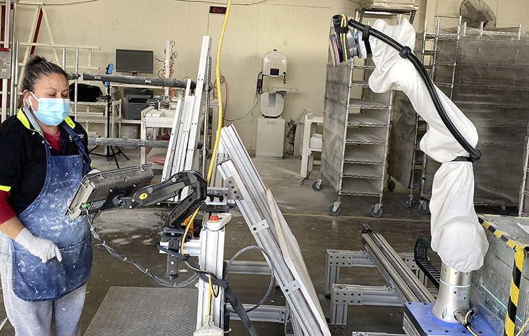 An EnVata worker supervises the Rizon sanding robot.