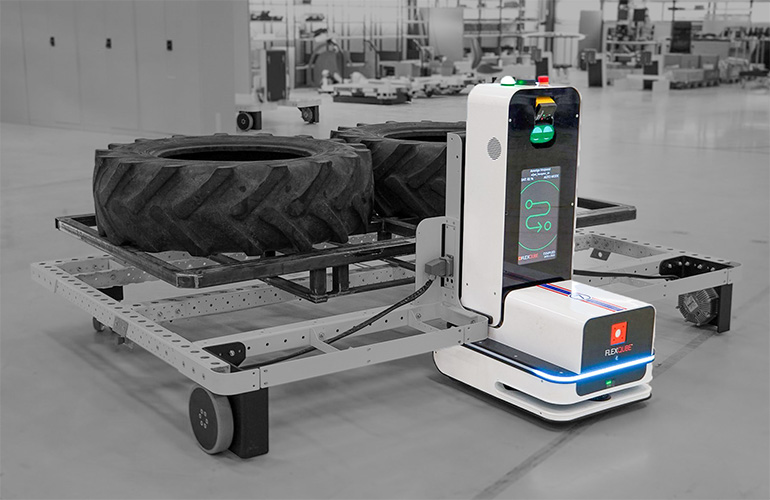 a Flexqube navigator AMR moves a rack with large tractor tires.