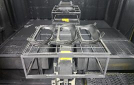 Automotive parts are brought to a paint booth, where they’ll be sprayed with a low-gloss paint that smooths out the surface and helps absorb light inside the vehicle.