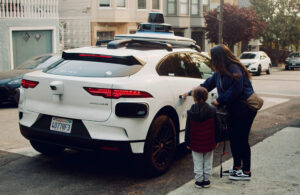 A woman and a child getting into a Waymo vehicle on a street in San Francisco.