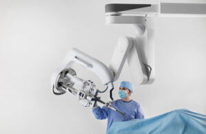 A person in scrubs and a mask interacting with an Intuitive da Vinci SP Surgical System.