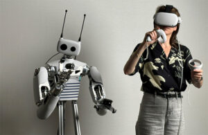 reachy robot next to a human with a visor and hand controller. Hugging Face acquired Pollen Robotics in April 2025.