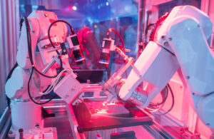 Two robotic arms working on an electronic assembly line.