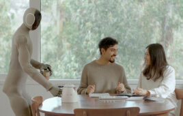 NEO Gamma placing down a teapot on a table next to two people having breakfast.