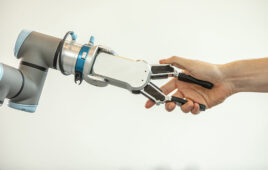 A person shaking hands with an cobot arm with an OnRobot two-fingered gripper. Odense Robotics works with Universal Robots and OnRobot.
