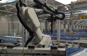 A Nomagic robotic arm picking items from bins on a conveyor belt.