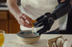 A person cracking an egg with a robotic hand.