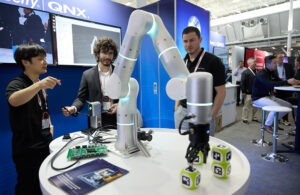 An image of a robotic arm picking up a block with a QR code on it at the 2024 Robotics Summit.