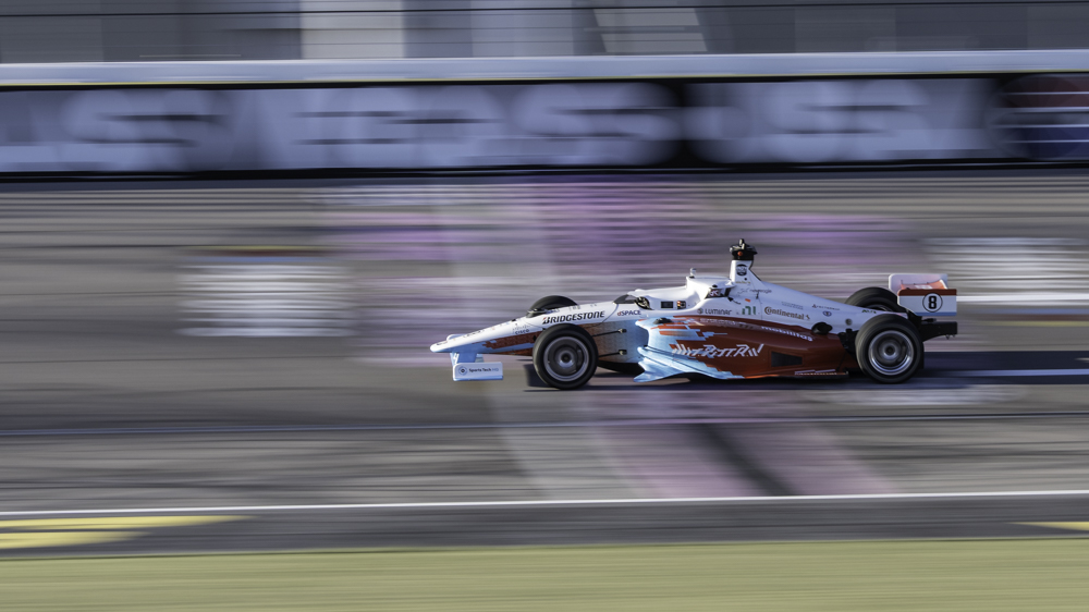 An Indy Autonomous Challenge racecar races across the finish line.