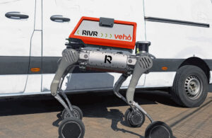 A RIVR robot waits next to a delivery van.