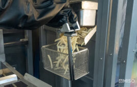 A Flippy robot from Miso Robotics gathering frozen fries in a fry basket.