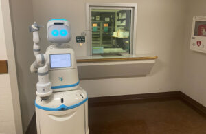 A Moxi robot standing at a pharmacy window.