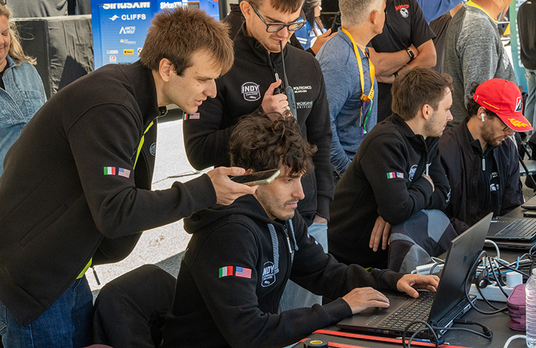 team polimove team members in front of computers in pits.