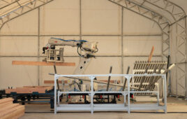 An ABB robot arm picking up a piece of wood. ABB is working with Cosmic Buildings on construction in LA.