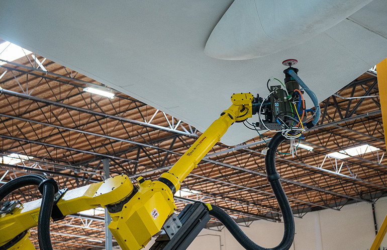 A robot buffs the surface of an aircraft wing. Physical AI could make programming robots easier.