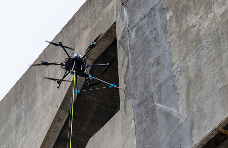 lucid bots drone spraying paint on a building wall.