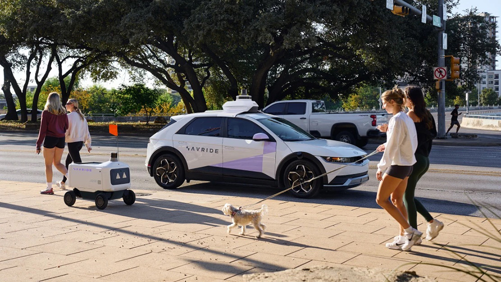 An autonomous vehicle and sidewalk delivery robot next to each other.
