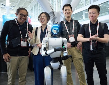 unitree G2 humanoid robot with group of attendees behind it.