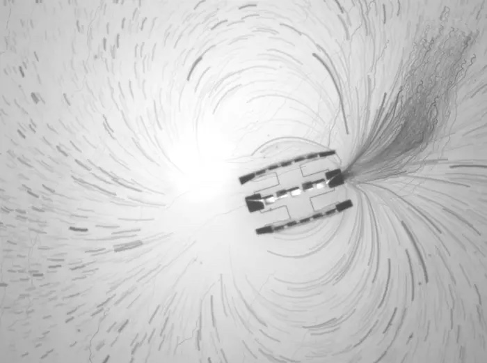 Um lapso de tempo projetado das trajetórias de partículas traçadoras perto de um robô que consiste em três motores interligados, conforme mostrado por pesquisadores da Universidade da Pensilvânia.