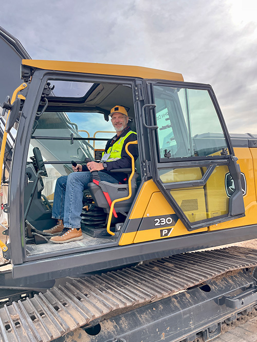 mike oitzman sits in the cab of a John Deere 230P excavator.