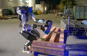 noble machines humanoid robot picks up a wooden board from a pile.