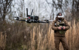 A PDW drone flying with an operator behind it.