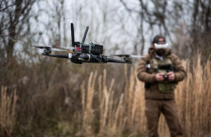 A PDW drone flying with an operator behind it.