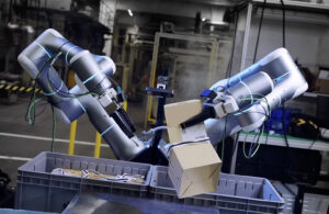 Two robot arms opening a box. Rhoda AI emerged from stealth in March 2026 to provide motion planning software.