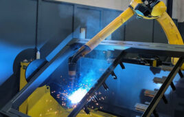 a yellow robot welds a facade frame.