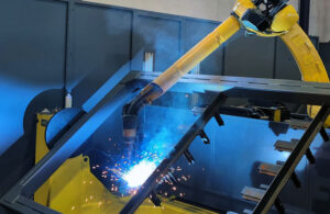 a yellow robot welds a facade frame.