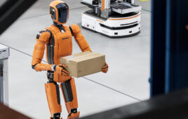A humanoid robot carrying a box in a warehouse.