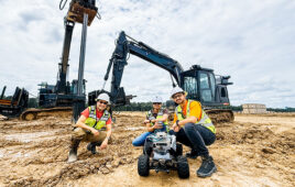 two workers stand behind a mobile robot equipped with sensors at a job site. | Credit: Built Robotics