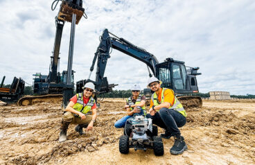 two workers stand behind a mobile robot equipped with sensors at a job site. | Credit: Built Robotics