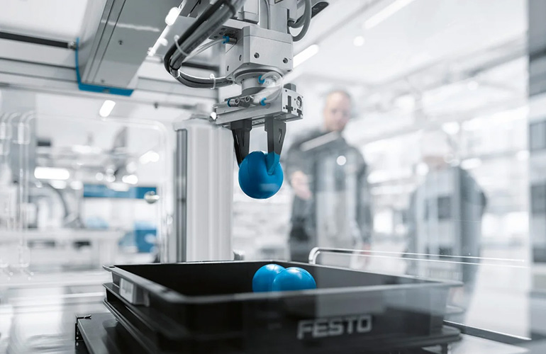 a robot picks up a foam ball in a workcell using GripperAI from Festo.