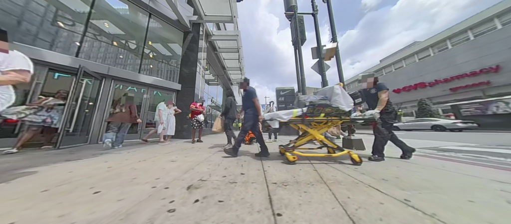 A view from the robot’s cameras shows autonomy with an extra safety layer: The robot autonomously yields to first responders moving a gurney. Simultaneously, the cloud VLM-watcher flags the unusual context, bringing a remote assistant in to monitor the scene.