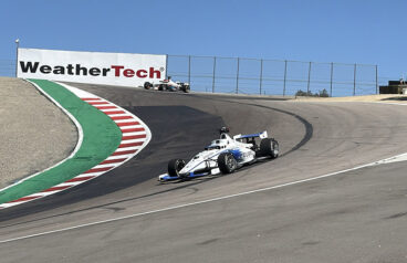 two race cars come through the famous corkscrew turn at Laguna Seca raceway.
