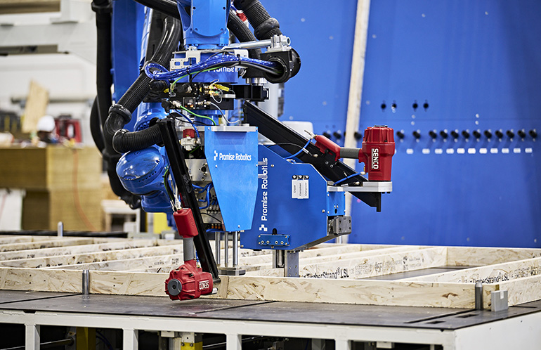 An industrial robot arm assembling a housing component. Promise Robotics is starting its Factory-as-a-Service in three North American cities.