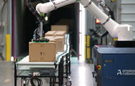 A robot arm picking a box from a conveyor belt.