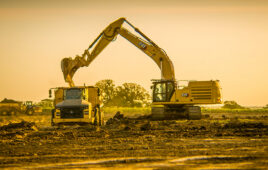 an autonomous loader drops dirt into a dump truck.
